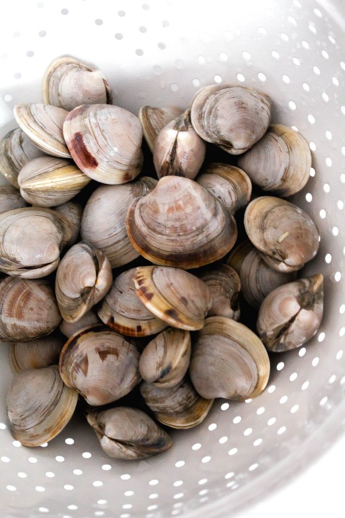 Linguine and clams with red pepper flakes sitting in a pink serving bowl.