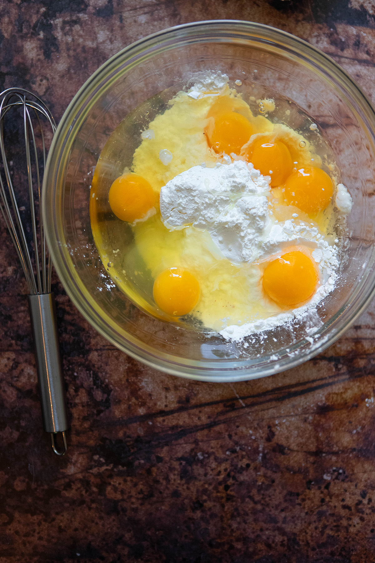 whisk next to bowl with eggs and corn starch