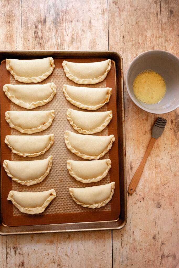 pumpkin pasties on a baking sheet with egg wash